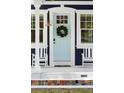 Close-up of a light blue front door adorned with a green wreath, flanked by white rocking chairs at 1521 E Harwood St, Orlando, FL 32803