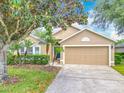 Charming single-story home featuring a well-manicured lawn, mature tree, and a two-car garage at 1961 Lochshyre Loop, Ocoee, FL 34761
