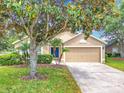 Inviting single-story home with lush landscaping, mature trees, and a two-car garage on a sunny day at 1961 Lochshyre Loop, Ocoee, FL 34761
