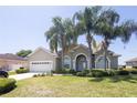 Inviting home showcases a well-manicured lawn, mature palms, and an attached two-car garage at 212 Terranova Blvd, Winter Haven, FL 33884