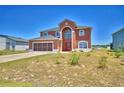 Inviting two-story home featuring a screened two car garage, arched entryway, and red front door at 2209 Pecos Ct, Poinciana, FL 34759