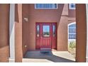 Elegant red front door with glass inserts and a 'welcome' mat, creating a warm and inviting entrance at 2209 Pecos Ct, Poinciana, FL 34759