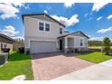 Front exterior featuring a two-car garage, lush lawn, and brick paved driveway leading to the home at 3134 Viceroy Ct, Poinciana, FL 34759