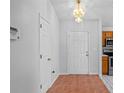 Hallway with tile floors, closet, and entry door with an ornate chandelier in the entry and kitchen view at 3220 Harpers Ferry Ct, Orlando, FL 32837