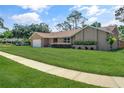 Well-manicured front yard with lush green grass and trimmed bushes, leading to a charming tan single-story home at 4833 Palm Tree Ct, Windermere, FL 34786