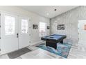 Foyer features a pool table, eye-catching light fixture, wood-look tile floors and textured accent wall at 5531 Dallas Blvd, Orlando, FL 32833