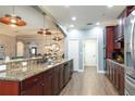 Spacious kitchen with granite counters, dark cabinets, stainless appliances and an open design connecting to dining area at 5799 Linen Bluff Pl, Leesburg, FL 34748