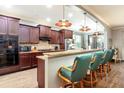 A kitchen with granite countertops, dark cabinets and backsplash, plus three barstools under the breakfast bar at 5799 Linen Bluff Pl, Leesburg, FL 34748