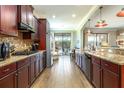 Spacious kitchen features granite countertops, modern appliances, dark wood cabinets, and wood flooring at 5799 Linen Bluff Pl, Leesburg, FL 34748