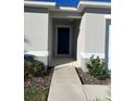 Inviting front entrance with a walkway leading to a stylish, dark-colored front door at 604 Sarner Pass Way, Winter Haven, FL 33881