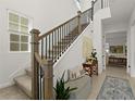 Bright entryway featuring a staircase with black iron railings, neutral decor, and tiled flooring at 7409 Inlet Pt, Celebration, FL 34747