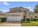Charming two-story home featuring a well-manicured lawn and an attached two-car garage at 8160 Sun Palm Dr, Kissimmee, FL 34747