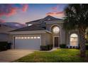 Sunset view of a charming two-story home featuring a well-manicured lawn and a two-car garage at 8160 Sun Palm Dr, Kissimmee, FL 34747