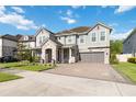 Beautiful two-story home with a gray exterior, stone accents, a paver driveway, and lush green lawn at 10626 Bonne Chance Dr, Orlando, FL 32832