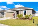 Single story home with two car garage, lawn and nice landscaping around the front entrance at 3761 Shoveler Ave, Leesburg, FL 34748