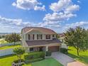 Charming two-story home featuring a well-manicured lawn, brick-paved driveway and mature landscaping at 4113 Longbow Dr, Clermont, FL 34711