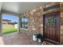 Inviting front porch with stone accents, a decorative wreath, and potted plants creating a warm welcome at 4113 Longbow Dr, Clermont, FL 34711