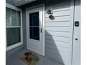 Home's porch with a white door, grey siding, an outdoor light fixture, and a cute welcome mat at 4244 Sun Village Ct # 160, New Smyrna Beach, FL 32169