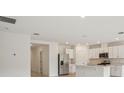 Open concept living space showcasing a modern kitchen with stainless steel appliances and white cabinetry at 4728 Jasmine Cir, Leesburg, FL 34748