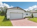 The house is a one story home with a two-car garage and a red brick driveway at 4732 Jasmine Cir, Leesburg, FL 34748