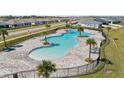 Aerial view of a community pool featuring palm trees, lounge chairs, and a fenced-in perimeter at 4981 Kaia Ave, Winter Haven, FL 33884
