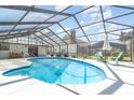 Screened in pool area featuring a sparkling blue pool, patio seating, and a lush backyard view at 71 Lazy Eight Dr, Port Orange, FL 32128