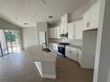 Modern kitchen features white cabinets, stainless appliances, a center island, and wood-look tile flooring at 738 Pointe Emerson Blvd, Apopka, FL 32703
