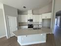 Bright kitchen with white cabinets, stainless steel appliances, large island, and modern backsplash at 738 Pointe Emerson Blvd, Apopka, FL 32703