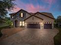 Elegant two-story home with stone accents, tile roof, and a three-car garage at dusk at 8625 Brixford St, Orlando, FL 32836