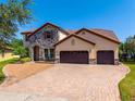 Charming two-story home featuring a stone facade, tile roof, three-car garage, and brick driveway at 8625 Brixford St, Orlando, FL 32836