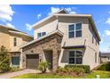 Two-story home with modern architectural details, stone accents, and lush landscaping at 9179 Sommerset Hills Dr, Davenport, FL 33896