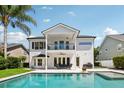 A refreshing backyard pool with patio furniture, a second-story balcony, and lush tropical landscaping at 9684 Sweetleaf St, Orlando, FL 32827