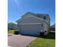 The side of this two-story house features an attached two-car garage and brick driveway at 1116 Myrtle Hammock Ln, Davenport, FL 33837