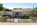 Inviting single-story home with a well-maintained lawn, lush greenery, and a secure black metal fence at 1122 Vassar St, Orlando, FL 32804