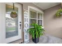 Cozy front porch with decorative 'HOME' sign, potted plants, and natural light from the window at 1701 Smoketree Cir, Apopka, FL 32712