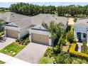 Aerial view of charming home with a two-car garage, brick driveway, landscaping, and a mature palm tree at 2026 Key Bay Trl, Kissimmee, FL 34747