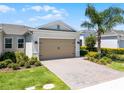 Charming home with a two-car garage, brick driveway, beautiful landscaping, and a mature palm tree at 2026 Key Bay Trl, Kissimmee, FL 34747