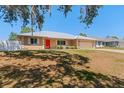 A charming single-story home features a silver metal roof, manicured lawn and a bright red front door at 2990 Mallard Dr, Deltona, FL 32738