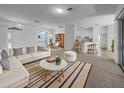 Bright living room with white sofa, striped rug, and open floor plan leading to the kitchen and dining area at 640 Westview Dr, Minneola, FL 34715