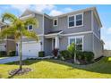 Charming grey two-story home featuring a well-manicured lawn and a two-car garage at 7649 Ragusa Way, Clermont, FL 34714