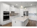 Bright, white kitchen features a large island, stainless steel appliances, and stylish pendant lighting at 7649 Ragusa Way, Clermont, FL 34714