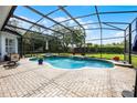 Screened-in pool with a waterfall feature, spa, and ample brick-paved deck space with lush landscaping at 11014 Hawkshead Ct, Windermere, FL 34786