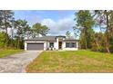 Charming single-story home with a gray driveway, inviting yellow front door, and well-maintained landscaping at 16908 Sw 44Th Cir, Ocala, FL 34473