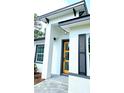 Close-up of a modern home's yellow front door framed by white columns and black accents at 16908 Sw 44Th Cir, Ocala, FL 34473