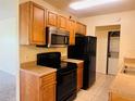 Functional kitchen featuring wooden cabinets, black appliances, and a view into the laundry area at 1695 Lee Rd # E214, Winter Park, FL 32789