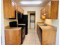 The kitchen features wood cabinets, black appliances and light colored tile floors at 1695 Lee Rd # E214, Winter Park, FL 32789