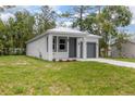 Cozy single-Gathering home featuring a well-manicured lawn, gray front door, and garage at 2259 3Rd Ave, Deland, FL 32724