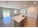 Modern kitchen island with sink and stainless dishwasher overlooking the living space and sliding glass doors at 141 Addle Hill Ct, Deland, FL 32720