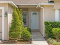 Close-up of the home's entrance, featuring a white front door, trimmed bushes, and a lantern at 14750 Hartford Run Dr, Orlando, FL 32828