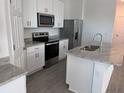 Modern kitchen featuring stainless steel appliances, granite countertops, and white cabinetry at 4716 Homestead Trl, St Cloud, FL 34772